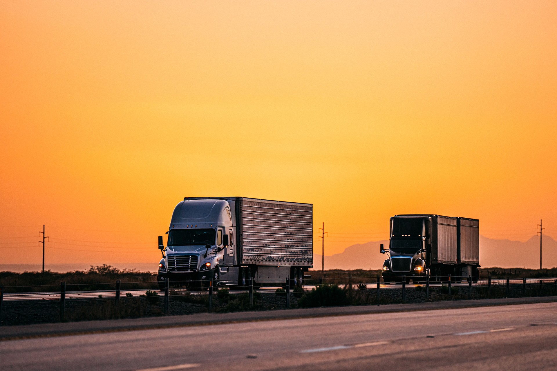 Two Semi Trucks on the Highway in El Paso, Texas with a Vibrant Orange Sunset